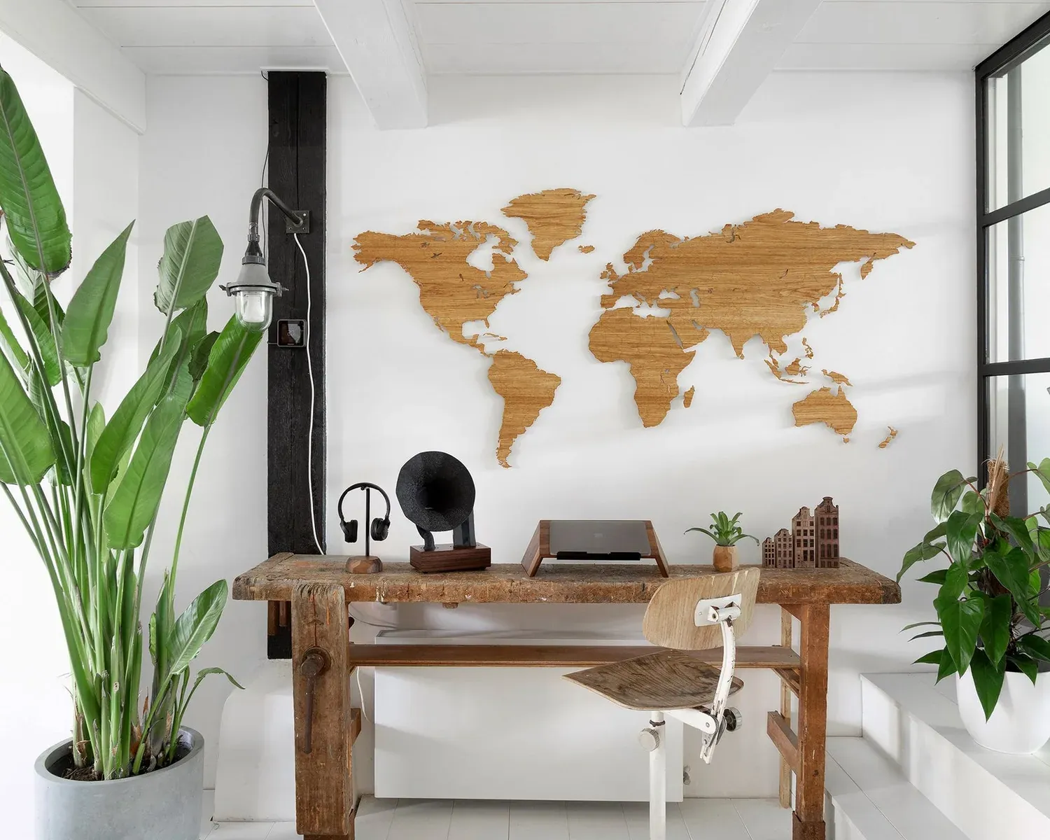 Single-tone oak Wooden Amsterdam world map installed above a wooden desk in a bright room